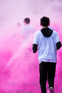 Rear view of man standing on pink umbrella