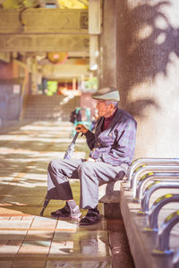 Side view of man wearing hat sitting outdoors