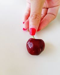 Close-up of hand holding strawberry over white background