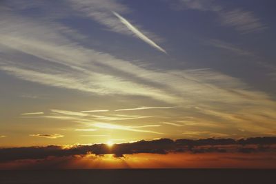 Low angle view of vapor trails in sky during sunset