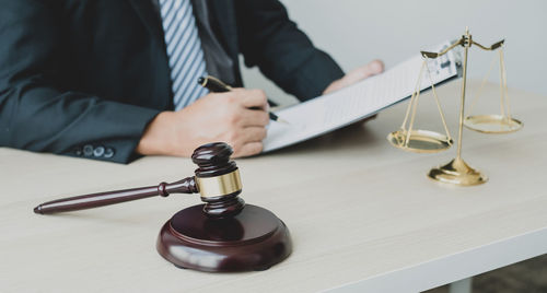 Midsection of lawyer holding gavel at table