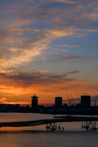 Silhouette bridge over river against sky during sunset