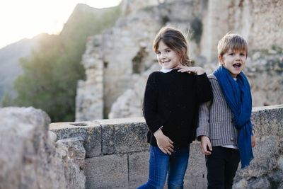 Boy and girl standing against stone wall