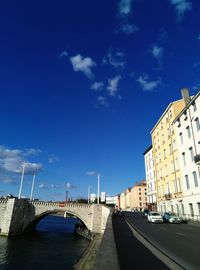 Road passing through city against blue sky