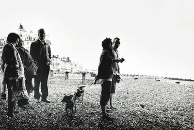 People walking on beach against clear sky