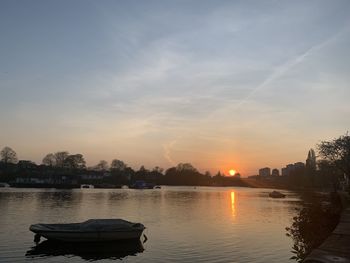 Boat in city against sky during sunset