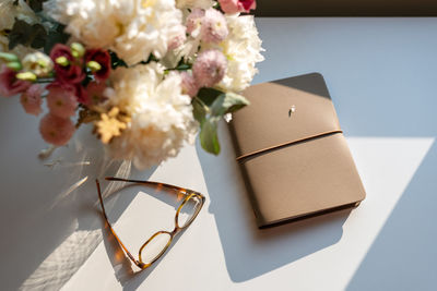 A bouquet of flowers and a notebook on the table in the sunset light.