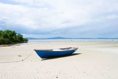 A blue fishing boat anchored in the sand of a beach. santo amaro, bahia.