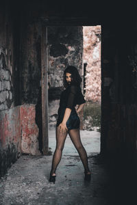 Full length portrait of woman standing in abandoned building