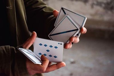 Midsection of man holding cards