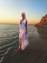 Woman on beach against sky during sunset