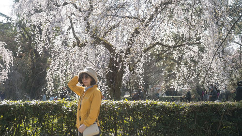 Young woman standing against trees