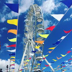 Low angle view of buntings and ferris wheel against sky