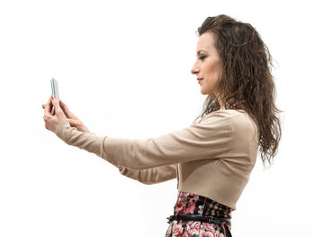 Side view of woman using smart phone against white background