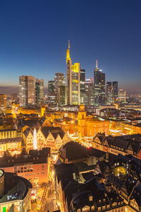 Illuminated buildings in city against clear sky