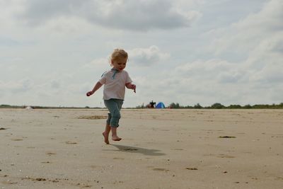 Full length of girl running at beach against sky