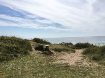 Empty bench at praa sands beach against sky