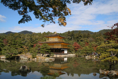 Built structure by lake and building against sky