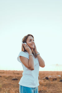 Portrait of smiling young woman standing against clear sky