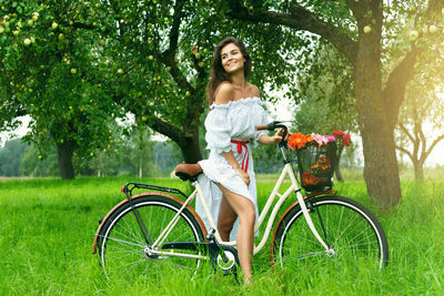 Portrait of young woman riding bicycle on field