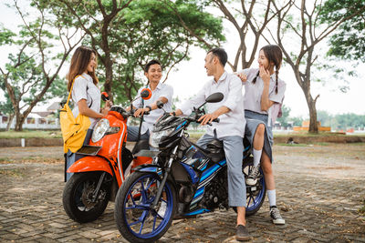 Side view of people riding motor scooter on road