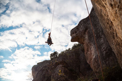 Low angle view of person on rock against sky