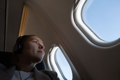 Woman seating in the airplane looking out of the window