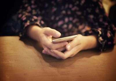 Midsection of woman using mobile phone on table