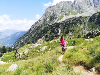 Rear view of people walking on mountain against sky