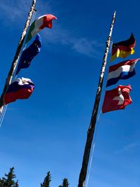 Low angle view of flags against clear blue sky