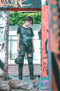 Full length of woman standing against graffiti wall