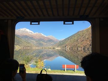 Woman photographing mountains and calm lake while traveling in train