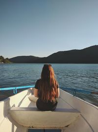 Rear view of woman sitting in rowboat on lake