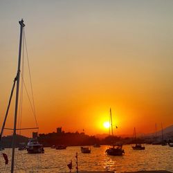 Sailboats moored on sea against sky during sunset