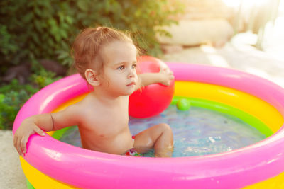 Close-up of thoughtful shirtless girl sitting in wading pool