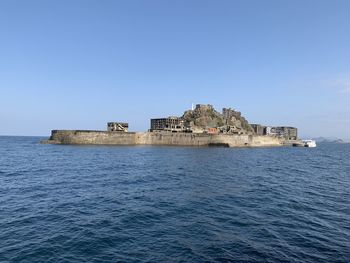 Buildings by sea against clear blue sky