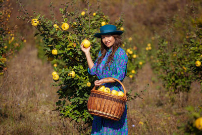 Woman wearing hat standing by plants in basket