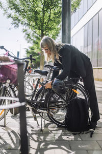 Businesswoman locking bicycle at parking station