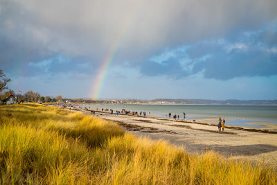 Scenic view of beach against rainbow in sky