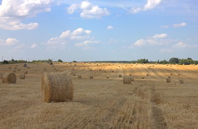 Hay bales on field against sky