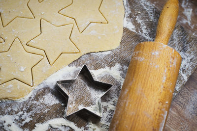 High angle view of star shape cookies with rolling pin and cutter on table