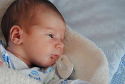 Close-up of cute baby lying on bed at home