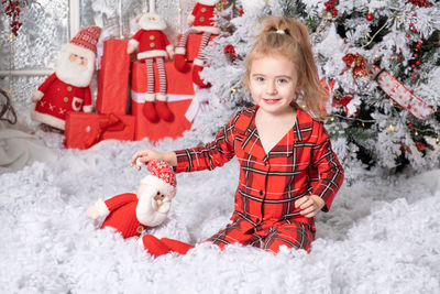 Cute baby girl playing with santa claus toy in christmas decorated room. merry christmas concept