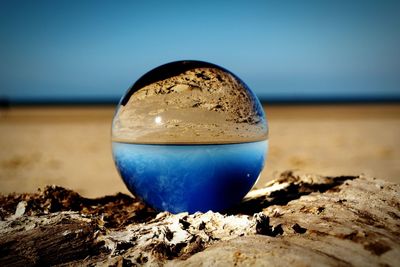 Close-up of water on beach against clear blue sky