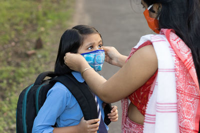An indian school girl child going to school again after pandemic with her mother 