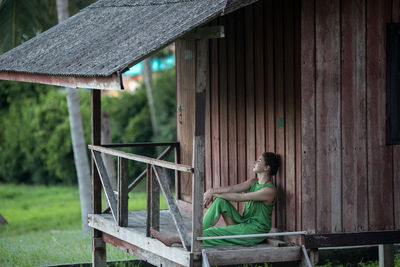 Man sitting on bench against building