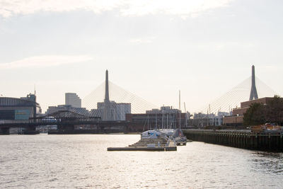 Sailboats in river against cloudy sky