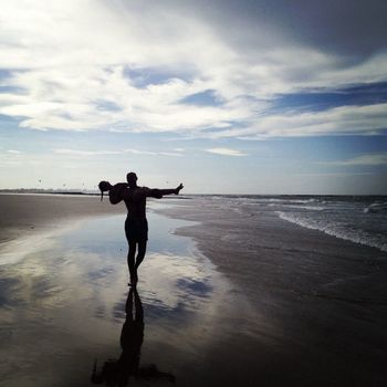 Man carrying daughter across wet beach