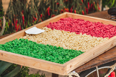 Fresh green, white and red orecchiette or orecchietta pasta drying under the sun on a wooden board