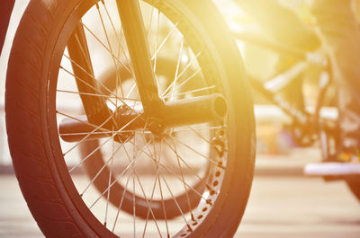 Close-up of bicycle wheel on street during sunny day